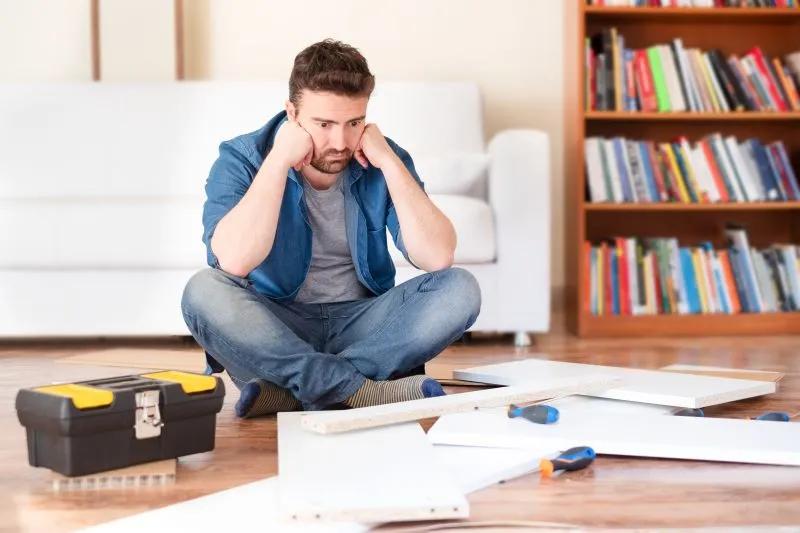 diy image of man sitting on floor looking like he cant put the cabinet together.